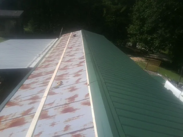Old rusted panels beside newly installed green metal roofing — Wind Damage Roof Repair by Roofing Brothers in Ijamsville
