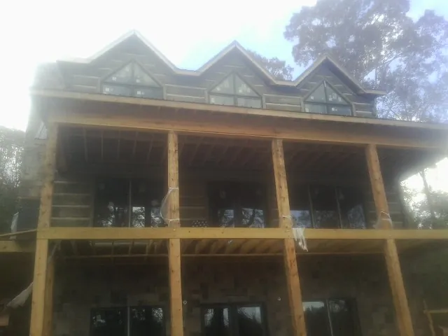 Dormers and porch framing on a large log home under construction — Roof Coating work by our crew in Ijamsville