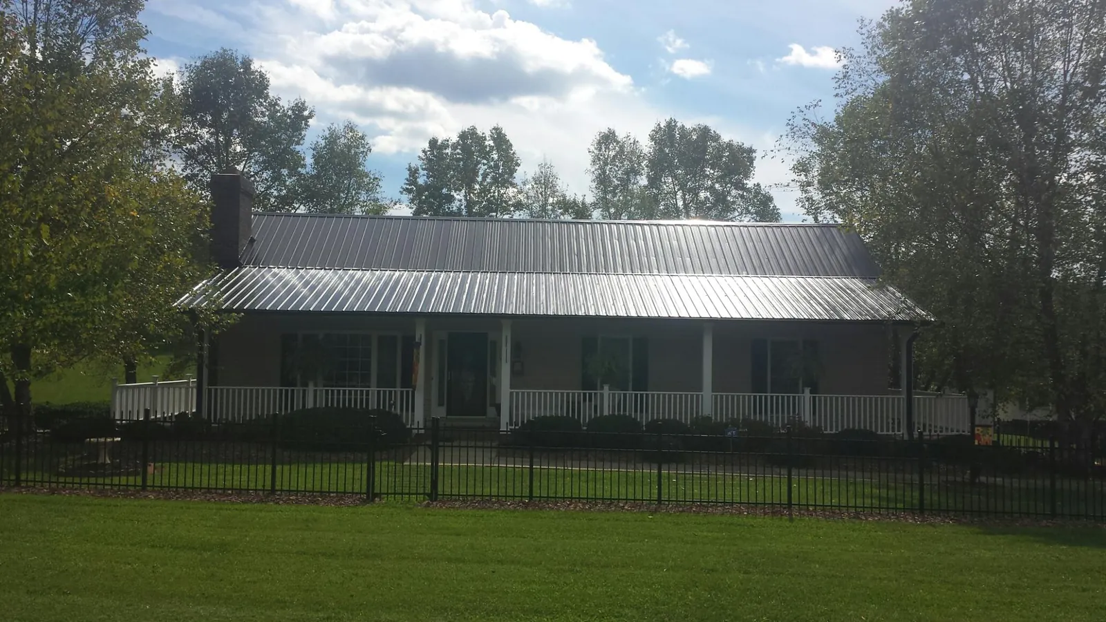 Gray metal roof on a brick ranch with a full width front porch — Gutter Guard Installation work by our crew in Ijamsville