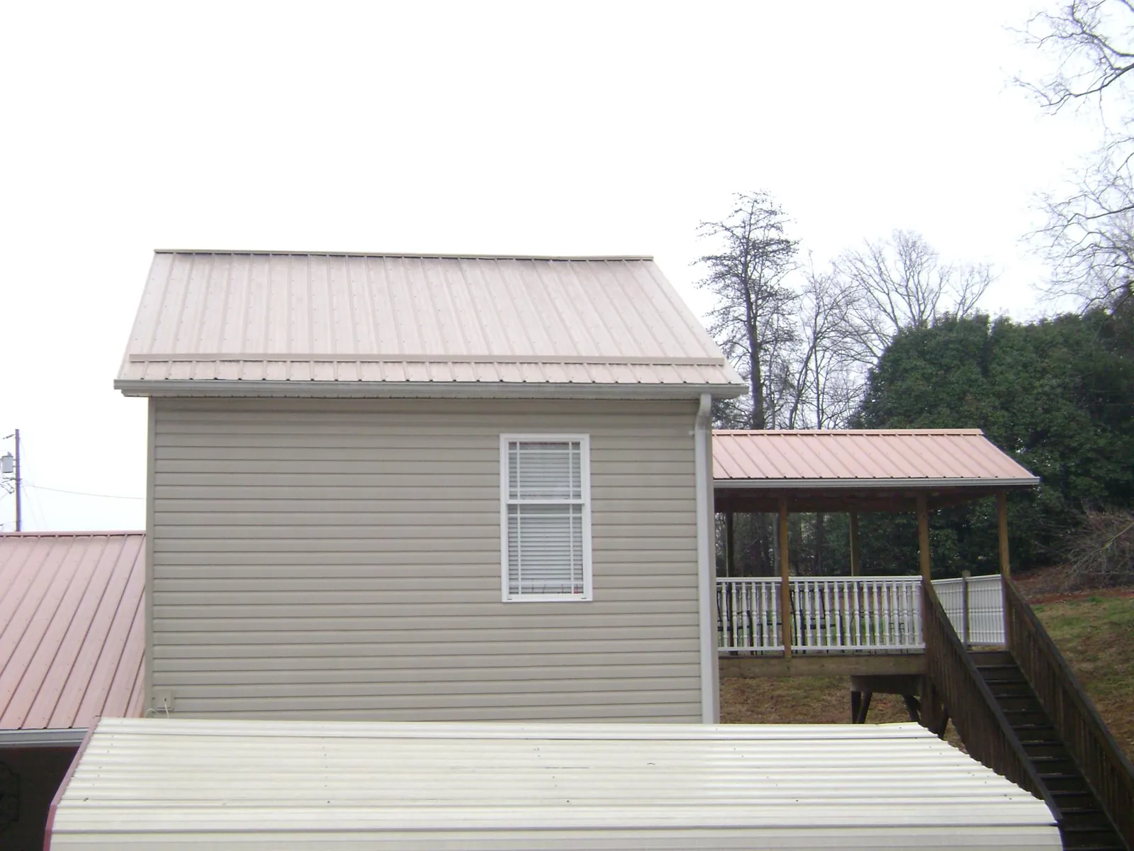 Tan metal roofs on a two story addition and attached porch, from a Roof Replacement job in Ijamsville